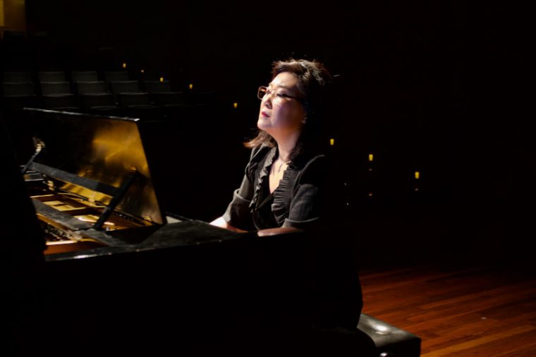 La pianista Liza Chung tocando un piano negro.